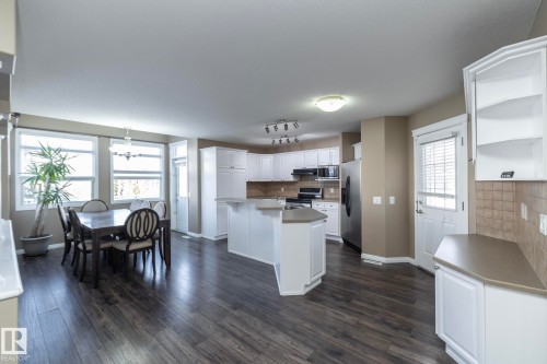 Kitchen featuring white cabinetry, backsplash, open shelves, an island with sink, and dark wood-style flooring - 16454 61A Street, Edmonton, AB - Indoor