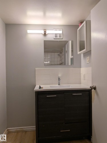 Full bathroom featuring vanity, light wood-style flooring, backsplash, and a shower - 109 7220 144 Avenue, Edmonton, AB - Indoor