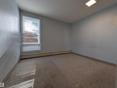 Spare room with carpet flooring, a baseboard radiator, and a textured ceiling - 109 7220 144 Avenue, Edmonton, AB - Indoor Photo Showing Other Room