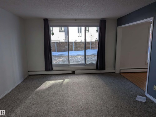 Carpeted spare room with a textured ceiling and a baseboard radiator - 109 7220 144 Avenue, Edmonton, AB - Indoor Photo Showing Other Room