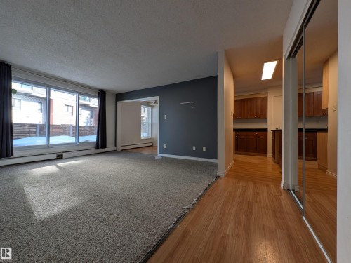 Unfurnished living room with a textured ceiling, a baseboard heating unit, and light wood-style flooring - 109 7220 144 Avenue, Edmonton, AB - Indoor Photo Showing Other Room