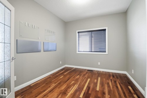Empty room with dark wood-style flooring and a textured ceiling - 12634 16A Avenue, Edmonton, AB - Indoor Photo Showing Other Room
