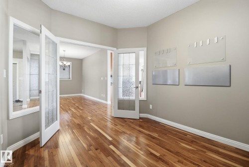 Foyer entrance with hardwood / wood-style floors, french doors, and a chandelier - 12634 16A Avenue, Edmonton, AB - Indoor Photo Showing Other Room