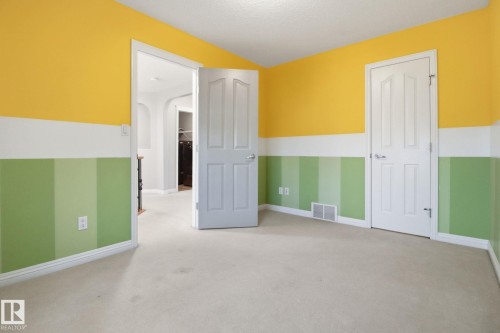 Unfurnished bedroom featuring light colored carpet, arched walkways, and a textured ceiling - 12634 16A Avenue, Edmonton, AB - Indoor