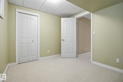 Unfurnished bedroom featuring a drop ceiling, carpet flooring, and a closet - 12634 16A Avenue, Edmonton, AB - Indoor