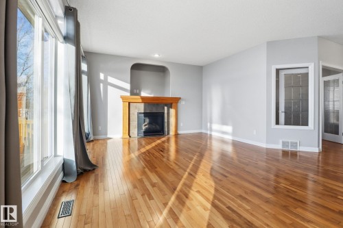 Unfurnished living room with hardwood / wood-style flooring, plenty of natural light, and a tile fireplace - 12634 16A Avenue, Edmonton, AB - Indoor Photo Showing Living Room With Fireplace