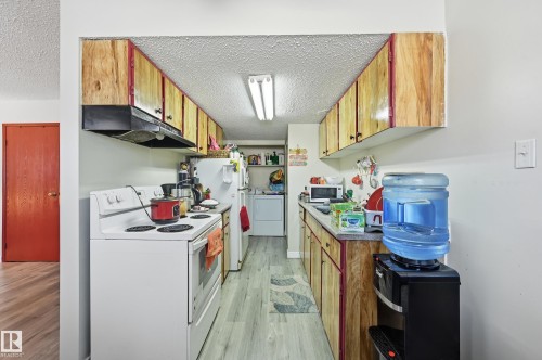 Kitchen with white appliances, a textured ceiling, light wood-style floors, light countertops, and wood finish cabinetry - 1482 Lakewood Road W, Edmonton, AB - Indoor Photo Showing Kitchen