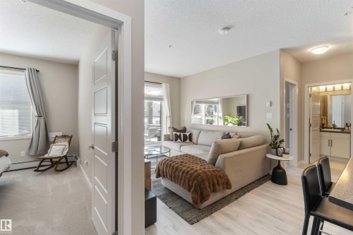 Living area with a textured ceiling and baseboard heating - 103 320 Ambleside Link Link Sw, Edmonton, AB - Indoor Photo Showing Living Room