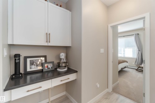 Corridor with a desk, a baseboard heating unit, and light wood-style flooring - 103 320 Ambleside Link Link Sw, Edmonton, AB - Indoor Photo Showing Other Room