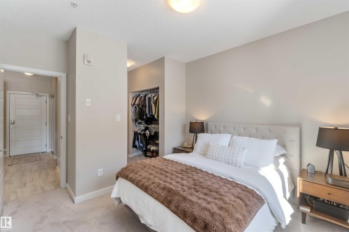 Bedroom featuring light carpet and a walk in closet - 103 320 Ambleside Link Link Sw, Edmonton, AB - Indoor Photo Showing Bedroom