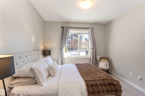 Carpeted bedroom with baseboards and a textured ceiling - 103 320 Ambleside Link Link Sw, Edmonton, AB - Indoor Photo Showing Bedroom