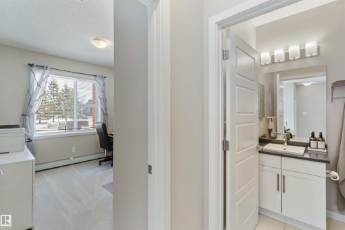 Half bathroom featuring vanity, a baseboard heating unit, light colored carpet, and a textured ceiling - 103 320 Ambleside Link Link Sw, Edmonton, AB - Indoor Photo Showing Laundry Room