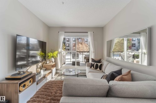 Living room featuring a textured ceiling - 103 320 Ambleside Link Link Sw, Edmonton, AB - Indoor Photo Showing Living Room