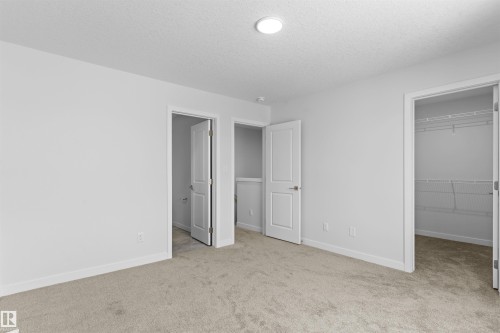 Unfurnished bedroom with a walk in closet, light colored carpet, and a textured ceiling - 320 Munn Way, Leduc, AB - Indoor Photo Showing Other Room
