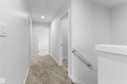 Corridor with light colored carpet and an upstairs landing - 