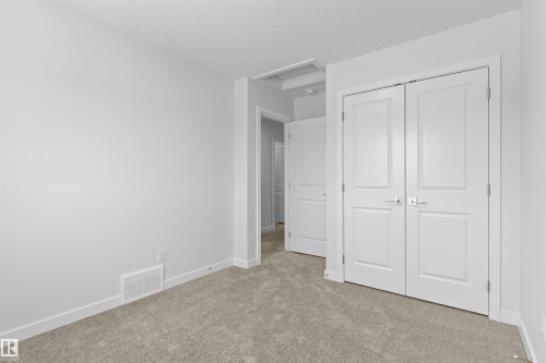 Unfurnished bedroom featuring carpet floors, a textured ceiling, and a closet - 320 Munn Way, Leduc, AB - Indoor