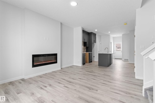 Unfurnished living room featuring a glass covered fireplace, recessed lighting, and light wood finished floors - 320 Munn Way, Leduc, AB - Indoor Photo Showing Living Room With Fireplace