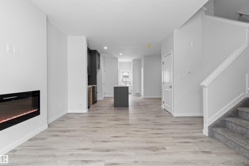 Unfurnished living room with light wood-style floors, a glass covered fireplace, and recessed lighting - 320 Munn Way, Leduc, AB - Indoor With Fireplace