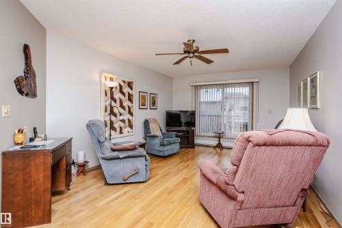 Living room featuring a ceiling fan, light wood-style floors, a textured ceiling, and baseboard heating - 408 10935 21 Avenue, Edmonton, AB - Indoor Photo Showing Living Room