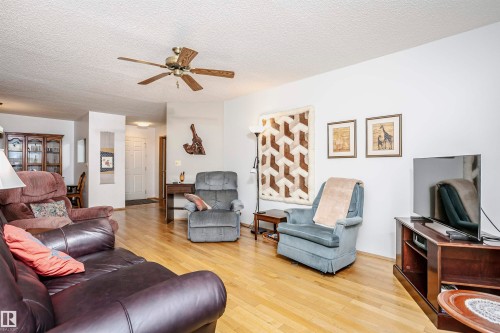 Living room featuring a textured ceiling, light wood-style floors, and a ceiling fan - 408 10935 21 Avenue, Edmonton, AB - Indoor Photo Showing Living Room