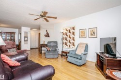 Living room featuring a textured ceiling, light wood-style floors, and a ceiling fan - 