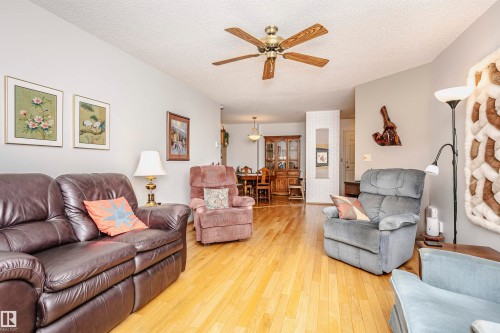 Living area with a ceiling fan, hardwood / wood-style floors, and a textured ceiling - 408 10935 21 Avenue, Edmonton, AB - Indoor Photo Showing Living Room