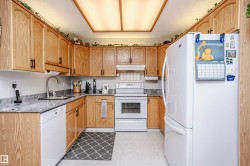 Kitchen featuring white appliances, dark stone counters, light tile patterned flooring, and a textured ceiling - 