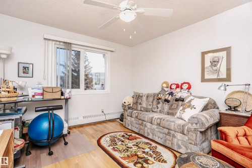 Living area with a baseboard radiator, wood finished floors, ceiling fan, and a textured ceiling - 408 10935 21 Avenue, Edmonton, AB - Indoor Photo Showing Other Room