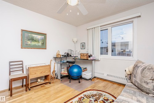 Office space with a ceiling fan, light wood finished floors, a baseboard radiator, and a textured ceiling - 408 10935 21 Avenue, Edmonton, AB - Indoor Photo Showing Other Room