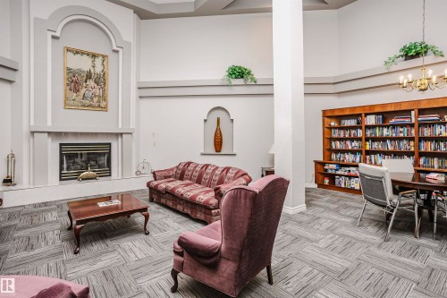 Carpeted living room featuring a high ceiling, a tile fireplace, and suspended lighting - 408 10935 21 Avenue, Edmonton, AB - Indoor With Fireplace