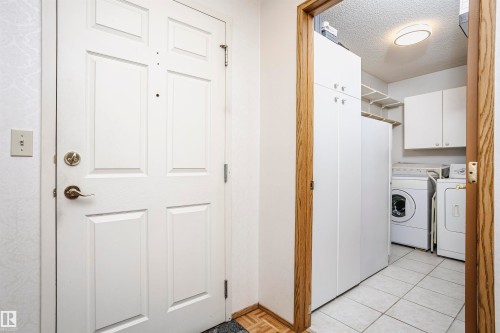 Laundry room with a textured ceiling, washing machine and clothes dryer, and cabinet space - 408 10935 21 Avenue, Edmonton, AB - Indoor Photo Showing Laundry Room