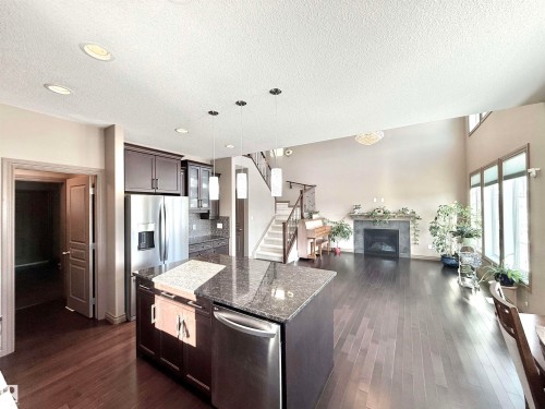 Kitchen with stainless steel appliances, dark stone countertops, pendant lighting, dark wood finish cabinetry, and open floor plan - 1019 174 Street, Edmonton, AB - Indoor Photo Showing Kitchen With Stainless Steel Kitchen With Upgraded Kitchen