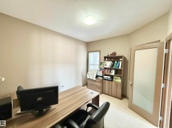 Office space with a textured ceiling and light colored carpet - 