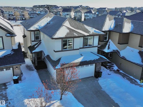 View of front of property featuring an attached garage, a residential view, concrete driveway, and a shingled roof - 1019 174 Street, Edmonton, AB - Outdoor