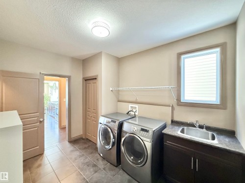 Laundry area featuring washer and clothes dryer, a textured ceiling, light tile patterned floors, and cabinet space - 1019 174 Street, Edmonton, AB - Indoor Photo Showing Laundry Room