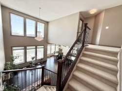 Stairway featuring wood finished floors, a high textured ceiling, and a chandelier - 