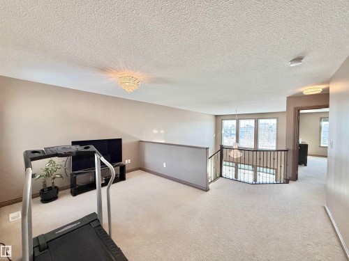Workout room with carpet flooring, a textured ceiling, and suspended lighting - 1019 174 Street, Edmonton, AB - Indoor Photo Showing Other Room