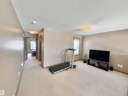 Exercise room featuring light colored carpet and a textured ceiling - 