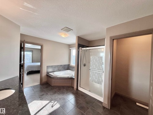 Ensuite bathroom featuring a garden tub, vanity, plenty of natural light, a stall shower, and a textured ceiling - 1019 174 Street, Edmonton, AB - Indoor Photo Showing Bathroom