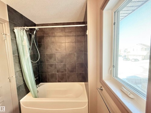 Full bathroom featuring a textured ceiling and shower / bathtub combination with curtain - 1019 174 Street, Edmonton, AB - Indoor Photo Showing Bathroom