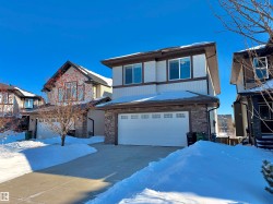View of front of property with an attached garage, stone siding, and concrete driveway - 
