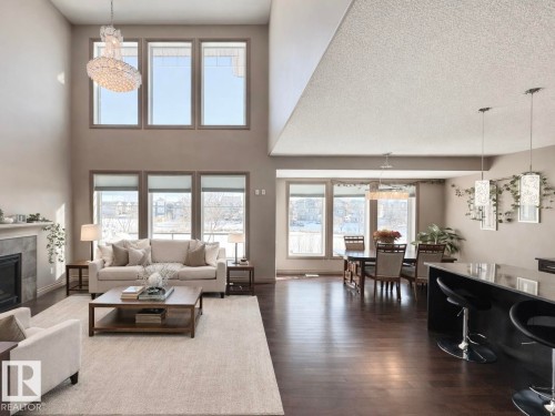 Living area featuring a chandelier, a tile fireplace, and dark wood-style flooring - 1019 174 Street, Edmonton, AB - Indoor Photo Showing Living Room With Fireplace