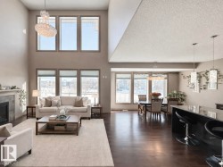 Living area featuring a chandelier, a tile fireplace, and dark wood-style flooring - 