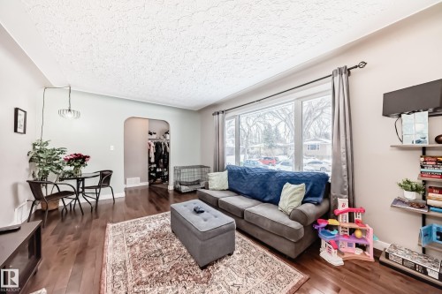 Living room featuring arched walkways, dark wood-style flooring, and a textured ceiling - 12332 129 Street, Edmonton, AB - Indoor Photo Showing Living Room