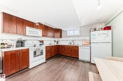 Basement Kitchen with white appliances, light wood finished floors, tasteful backsplash, and wood finish cabinetry - 