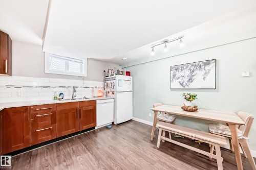 Kitchen featuring wood finish cabinetry, white appliances, light wood finished floors, and tasteful backsplash - 12332 129 Street, Edmonton, AB - Indoor Photo Showing Kitchen With Double Sink