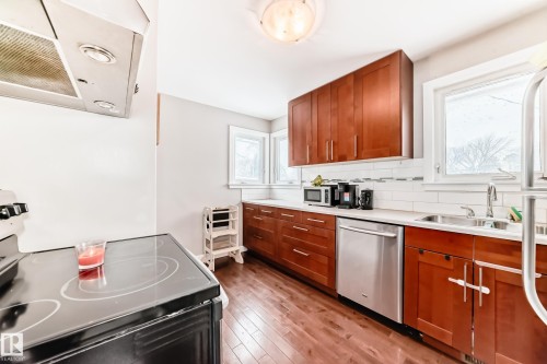 Kitchen featuring stainless steel appliances, exhaust hood, wood finish cabinets, and backsplash - 12332 129 Street, Edmonton, AB - Indoor Photo Showing Kitchen