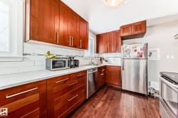 Kitchen featuring stainless steel appliances, backsplash, dark wood finished floors, wood finish cabinetry, and light stone counters - 