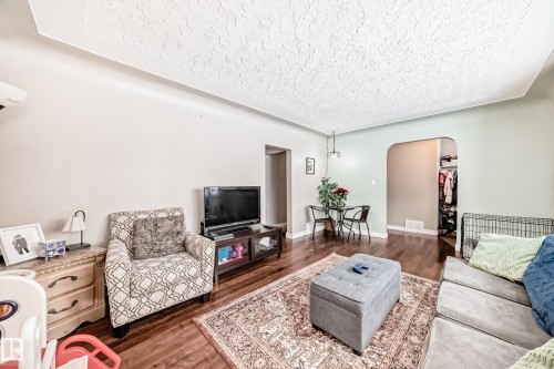 Living area featuring arched walkways, dark wood finished floors, and a textured ceiling - 12332 129 Street, Edmonton, AB - Indoor Photo Showing Living Room