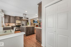 Kitchen featuring dark wood finish cabinetry, recessed lighting, a textured ceiling, stainless steel appliances, and dark wood finished floors - 